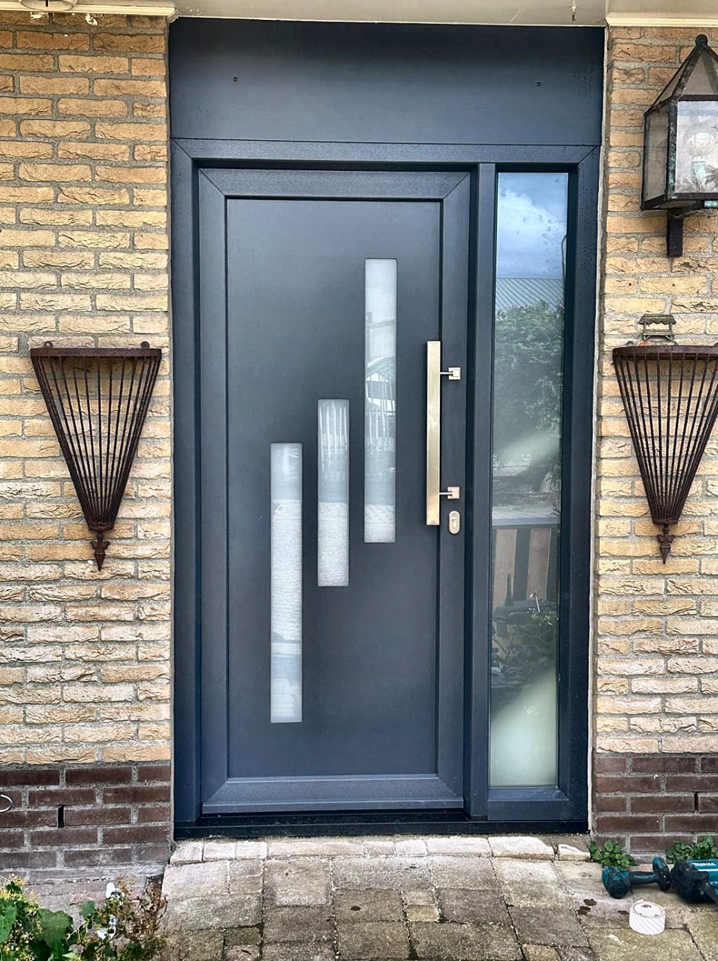 Antracietgrijze kunststof voordeur met glasstroken, zijlicht en rvs greep