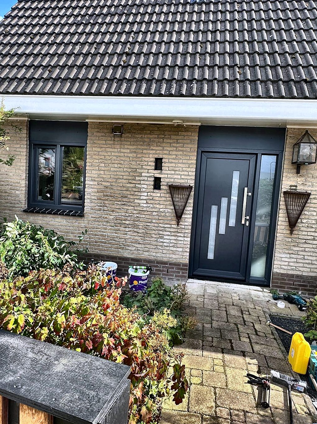 Nieuwe kunststof voordeur en zijraam in de voorgevel van een woning
